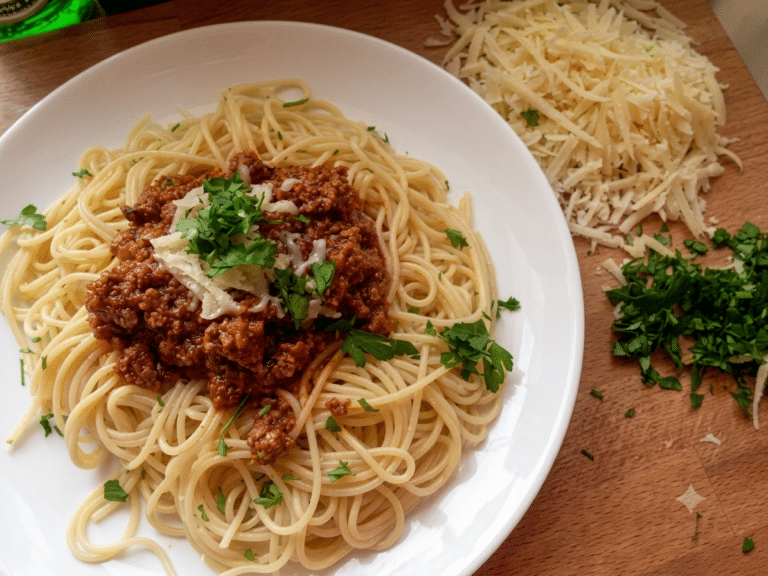 Talerz spaghetti alla Bolognese z gęstym sosem mięsno-pomidorowym, posypany parmezanem i świeżą pietruszką