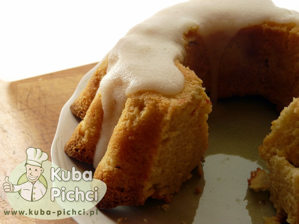 Babka cytrynowa w formie pierścienia polana białym lukrem cytrynowym, ustawiona na talerzu