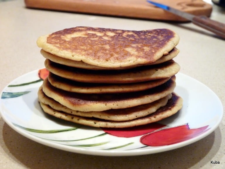 Stos puszystych amerykańskich pancakes polanych syropem klonowym na białym talerzu