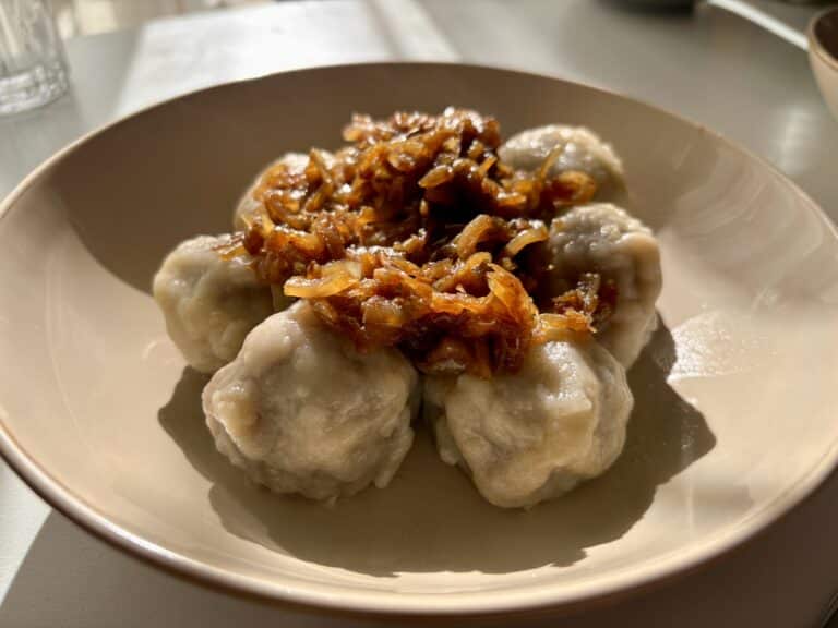 Pierogi bez lepienia podane na talerzu z przesmażoną cebulką