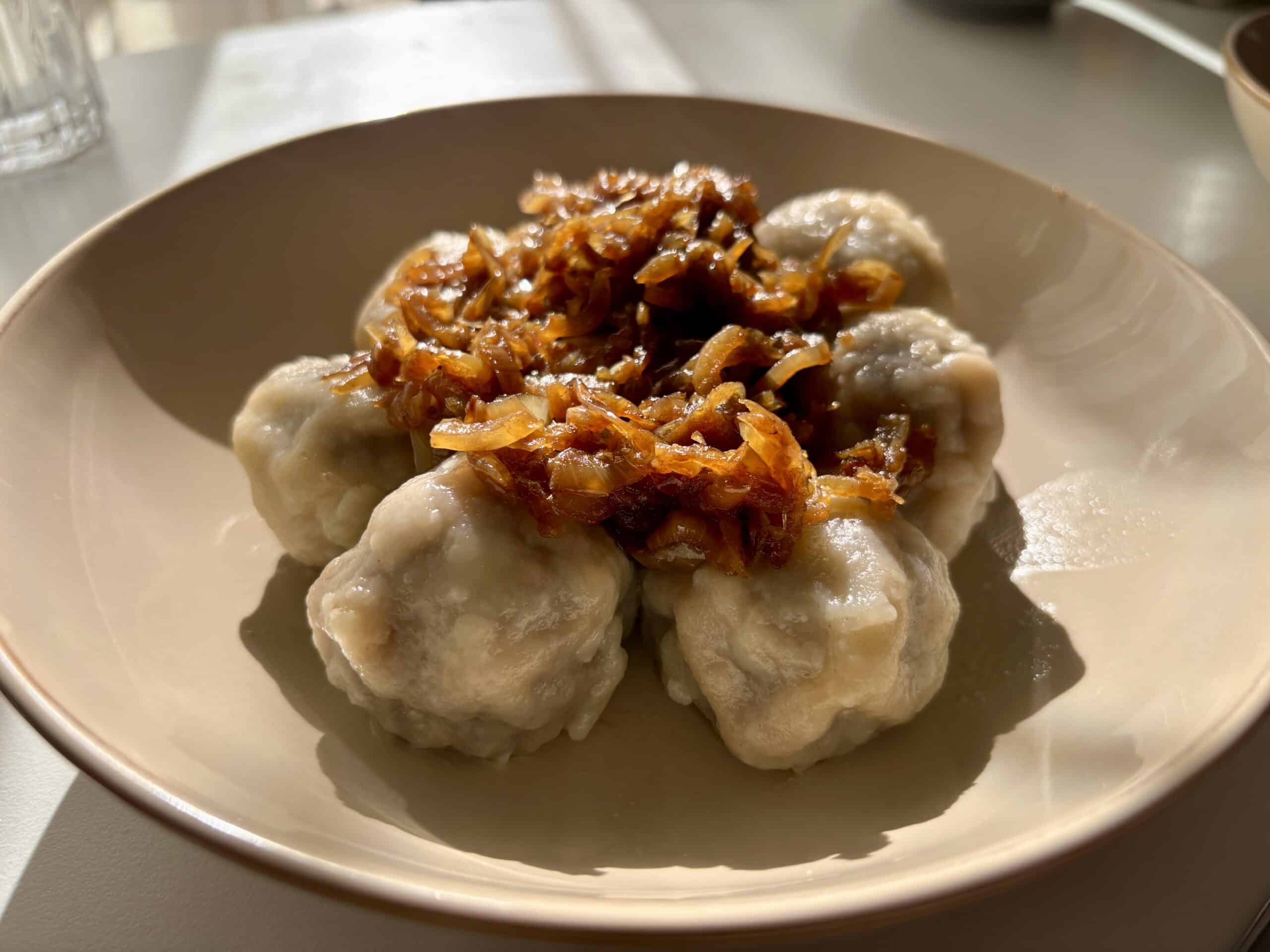Pierogi bez lepienia podane na talerzu z przesmażoną cebulką
